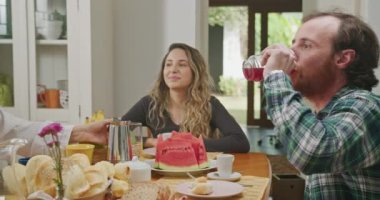 Family eating breakfast together. Mature couple with young adults son and daughter seated at morning table. Older parents and grown adults