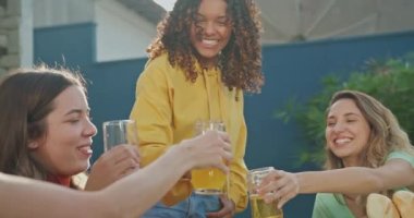 Group of diverse group of people at barbecue party together. Friends enjoying life and food together during sunny day outdoors drinking and eating.
