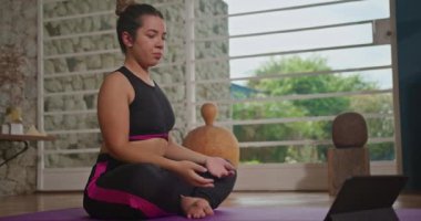 Person exercising at home. Woman stretching body in front of tablet technology. Female Person working out remotely