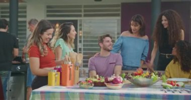 Diverse Hispanic group of friends enjoying barbecue party together. Brazilian people gathered together for food enjoying life. Happy people eat lunch