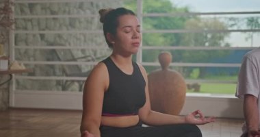 Young couple practicing mindful meditation at home living room. Two people with eyes closed meditating in contemplation together