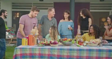 Group of hispanic diverse group of people standing at barbecue party together. Friends enjoying life together during sunny day outdoors
