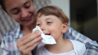 Mother wiping child runny nose. Parent lifestyle taking care while sick with flu