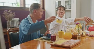 Happy older couple romantic time together at breakfast table. Senior mature man and woman eat food in morning breakfast meal