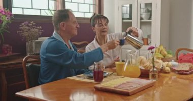 Senior couple eating breakfast in morning table. Mature husband and woman eat meal together. Older lifestyle relationship at home