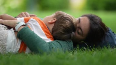 Mother lay on grass with child son. Parenting love and care. Mom laying outdoors with baby toddler