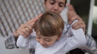 Playful mother and child together at home. Parent tapping son head with his own arms. Parenting happiness family lifestyle. Goofy mom
