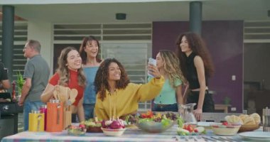 Diverse group of hispanic friends taking selfie together at lunch party in home backyard. Happy group of people take photo with smartphone