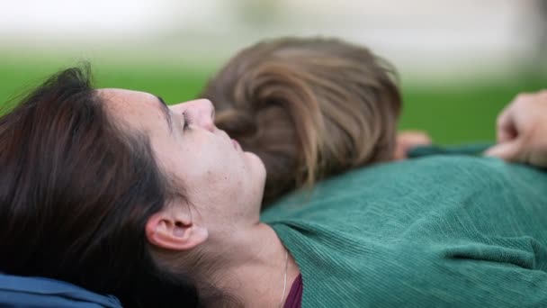 屋外公園で草の上に寝そべっている母親と子供の息子 週末のアクティビティを楽しむお母さんと子供の親の幸福コンセプトライフスタイル — ストック動画