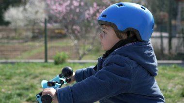 Bisikletli bir çocuk dışarıda kask koruması takıyor. Bisiklet süren çocuk manzarası