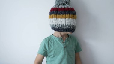 Şapkayla kaplı çocuk yüzü. Komik küçük çocuk yün kış aksesuarlarıyla kör oldu.