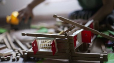 Küçük bir çocuk traktör buldozeriyle tahta ev oyuncağını yok ediyor. Erkek destroyer çocuk odasında oynuyor.