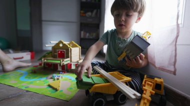 Evdeki oyun odasında oynayan küçük bir çocuk. Çocukluk gelişimi oyuncaklarla oynanır. Yoğunlaşmış erkek çocuk oyuna odaklanmış.