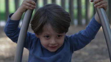 Çocuk oyun parkında dönüyor. Küçük bir çocuk paslanmaz çelik oyuncakla oyun alanında eğleniyor.