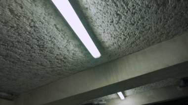 Yeraltı garajının floresan lambaları beton tavanda. Bina otoparkı