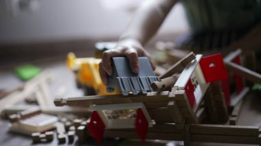 Küçük bir buldozer traktörüyle tahta ev oyuncağını yok eden bir çocuk. Evde oyun odasında oynayan küçük bir destroyer.