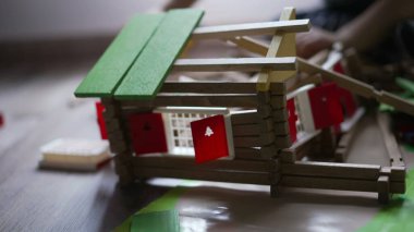 Küçük bir buldozer traktörüyle tahta ev oyuncağını yok eden bir çocuk. Evde oyun odasında oynayan küçük bir destroyer.