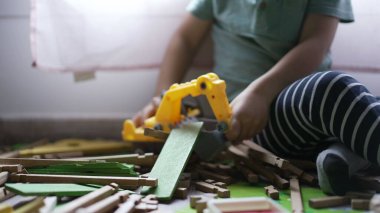 Çocuk buldozer traktör oyuncağıyla oynuyor. Oyun odasında odun topluyor. Kapalı çocuk elleri