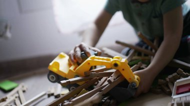 Küçük bir buldozer traktörüyle tahta ev oyuncağını yok eden bir çocuk. Evde oyun odasında oynayan küçük bir destroyer.