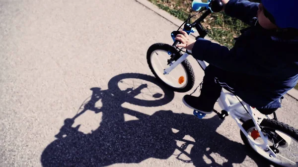 Child riding bicycle. Top view perspective of kid shadow outdoors