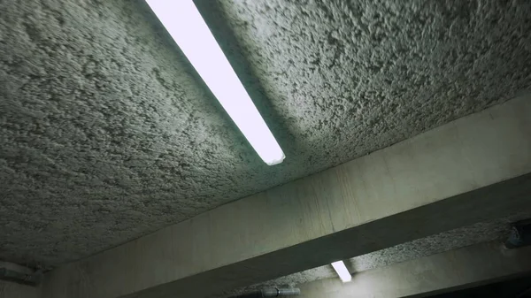 Yeraltı garajının floresan lambaları beton tavanda. Bina otoparkı