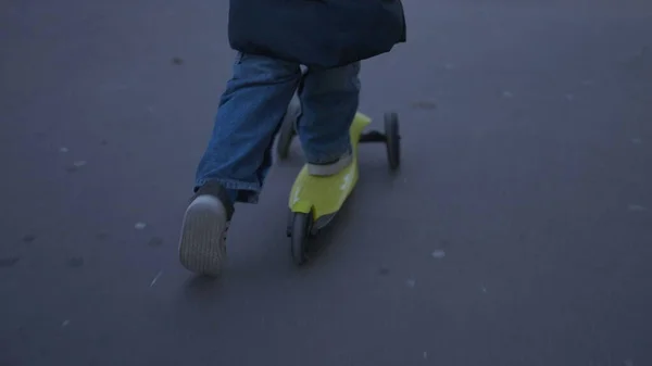 Child riding three wheeled scooter in city sidewalk2