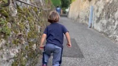 Effortful child walking uphill. One little boy climbing upward during weekend hiking activity with family