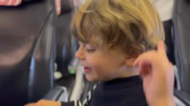 Back of child walking at plane aisle boarding plane. One small boy going for vacation searching for airplane seat. Kid walks inside airplane corridor