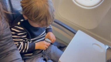 Passenger child putting seat belt on seated inside airplane waiting for plane to take off. Departure concept