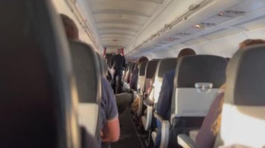  Inside plane corridor aisle with passengers seated in flight. Travel concept.