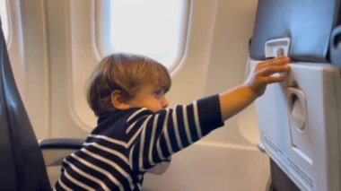Child opening tray table and accidentally getting hurt. Passenger boy seated inside plane