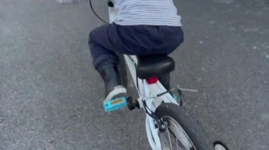 Child cyclist rides bike in urban street sidewalk. Active little boy riding bicycle.