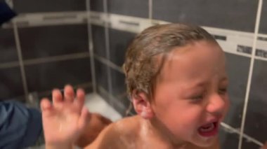 Washing upset baby toddler child in shower bath