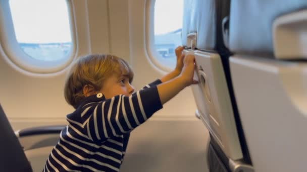 一个快乐的小乘客开放和关闭托盘表 快乐的小男孩坐飞机旅行 — 图库视频影像