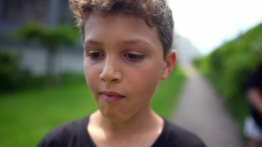 Çocuk dışarıda ağır çekimde yürüyor. Düşünceli çocuk.