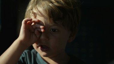 Çocuk trenle seyahat ederken gözünü ovalıyor. Yorgun çocuk, uykulu hissediyor.