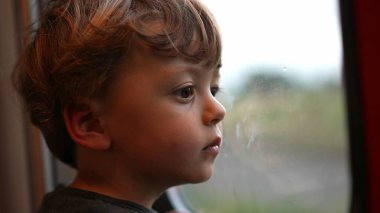 Küçük çocuk pencereden dışarı bakarak trenle seyahat ediyor.