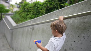 Bebek merdivenlerden inerken tırabzanlara tutunuyor. İstifa eden çocuk