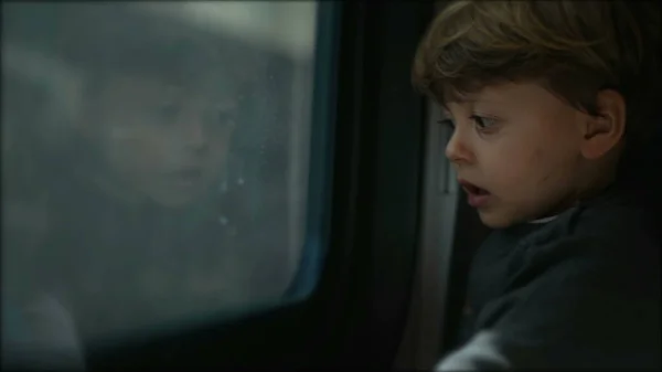 Little boy traveling by train staring outside through train window