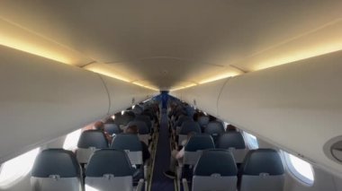 Plane cabin seen from the back. Passengers seated inside airplane