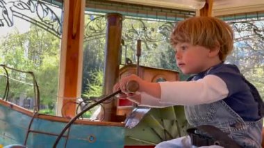 Happy child riding antique carousel. Joyful little boy rides toy at funfair park