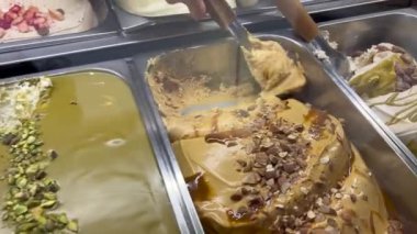 Scooping ice cream at gelateria shop in Italy. Italian gelato on display at store cafe
