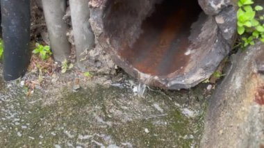Droplets falling in sewage system. Aged pipe closeup in street