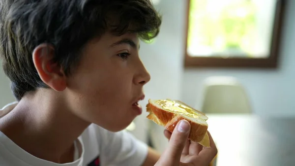 Young boy eating bread with jelly in morning breakfast