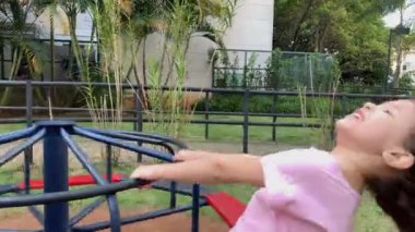 Two little girls playing at playground carousel. Female kids having fun