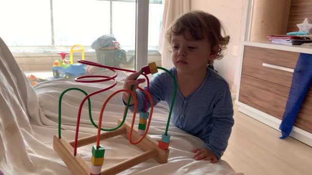 一个蹒跚学步的小男孩在家里玩创意玩具 穿着睡衣的小孩 坐在沙发上的童年生活方式 — 图库视频影像