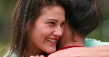 Happy young woman smiling and hugging female friend. Real life smile embrace