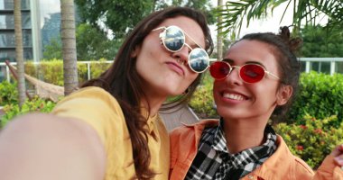 Two millenial girlfriends posing smiling at selfie