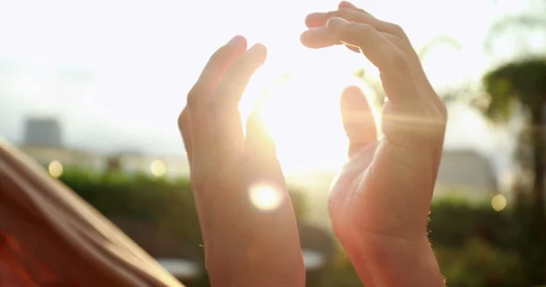 Close-up of hands joining together with sunlight flare in the background. Beautiful romantic moment between two lovers