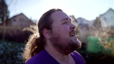 One overweight man taking a deep breath after run recovering from exercise with Breath vapor standing outside in the cold. A fat male person taking a break from run